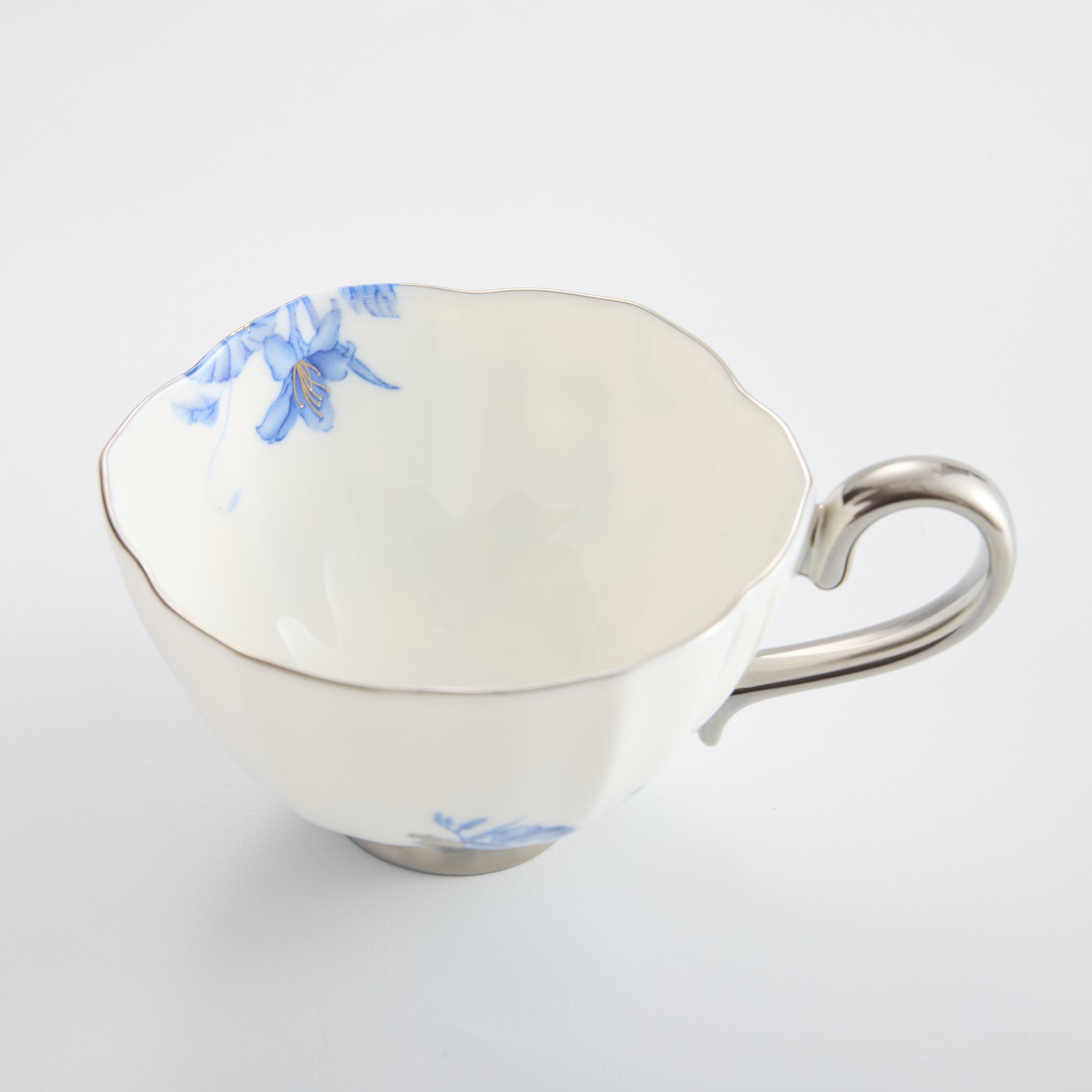 White ceramic teacup with blue floral design on a white background