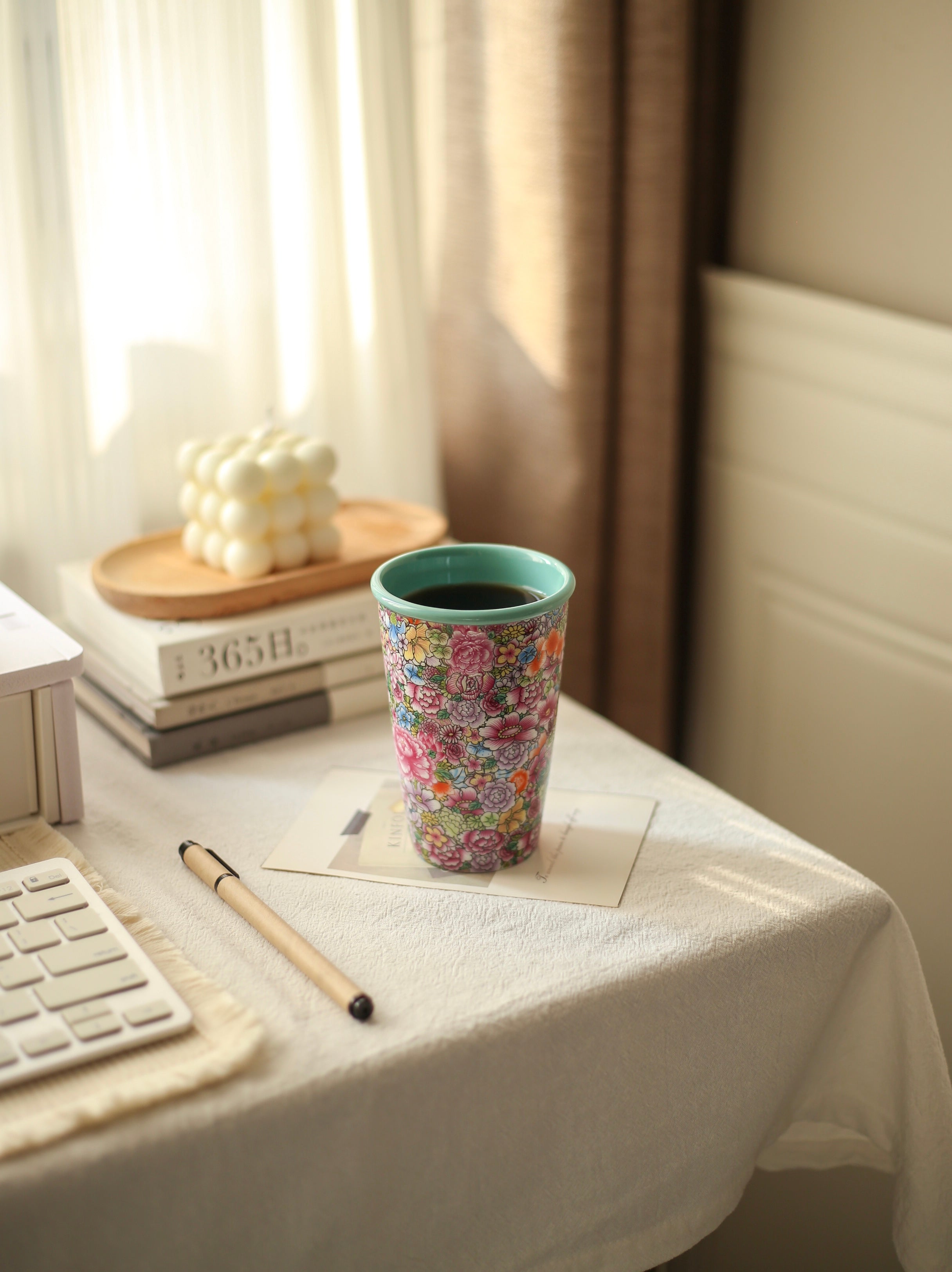 Colorful floral Falangcai mug on a desk with books and stationery