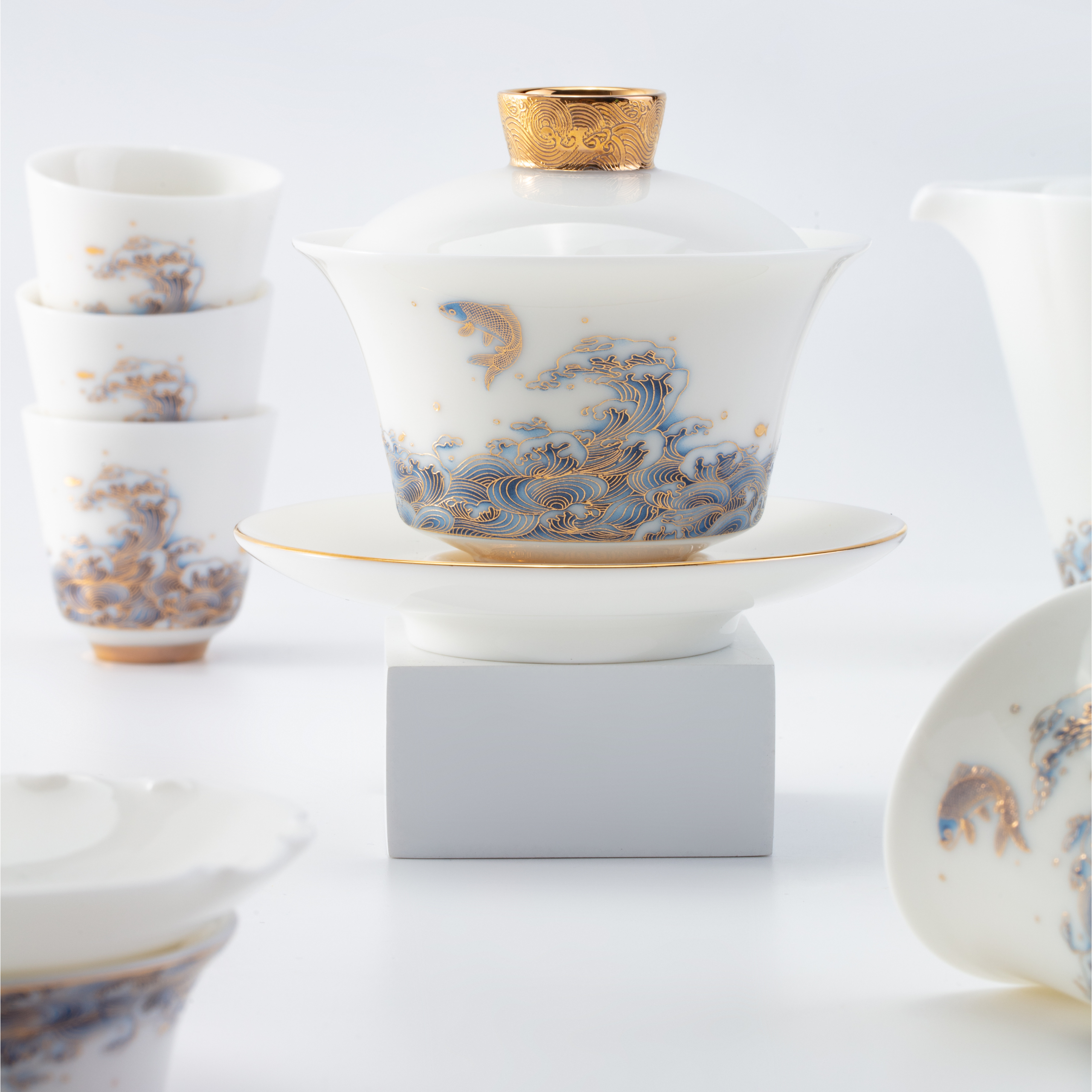 White ceramic teacup with gold and blue design on a white background