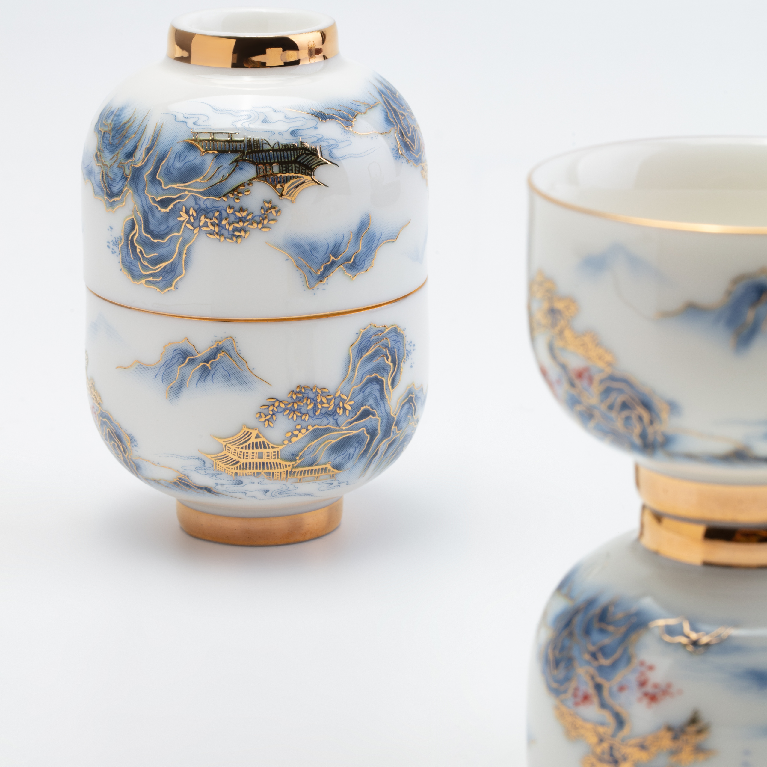 Ceramic jar and cup with blue and gold artistic designs on a white background