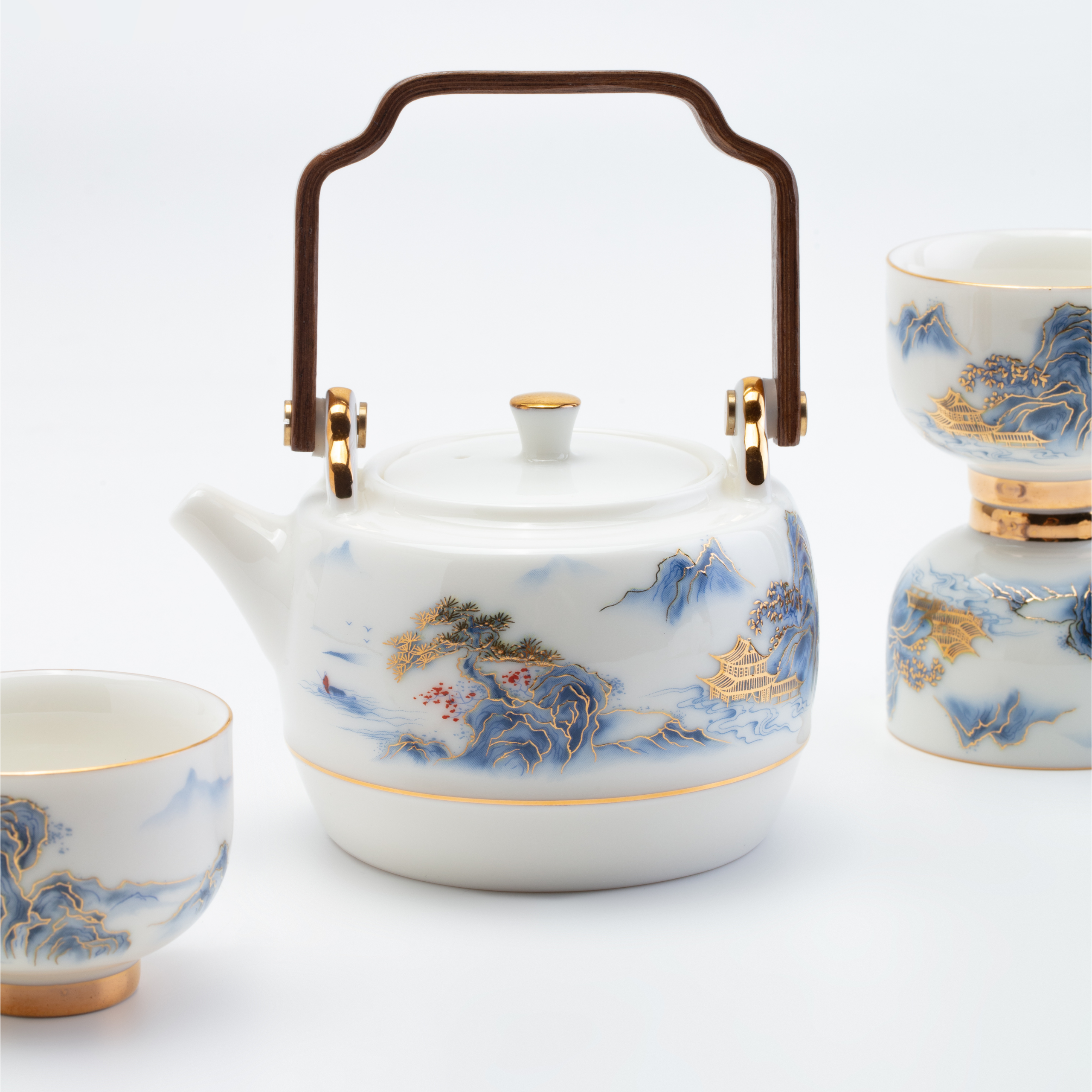 White teapot and cups with blue and gold floral patterns on a white background