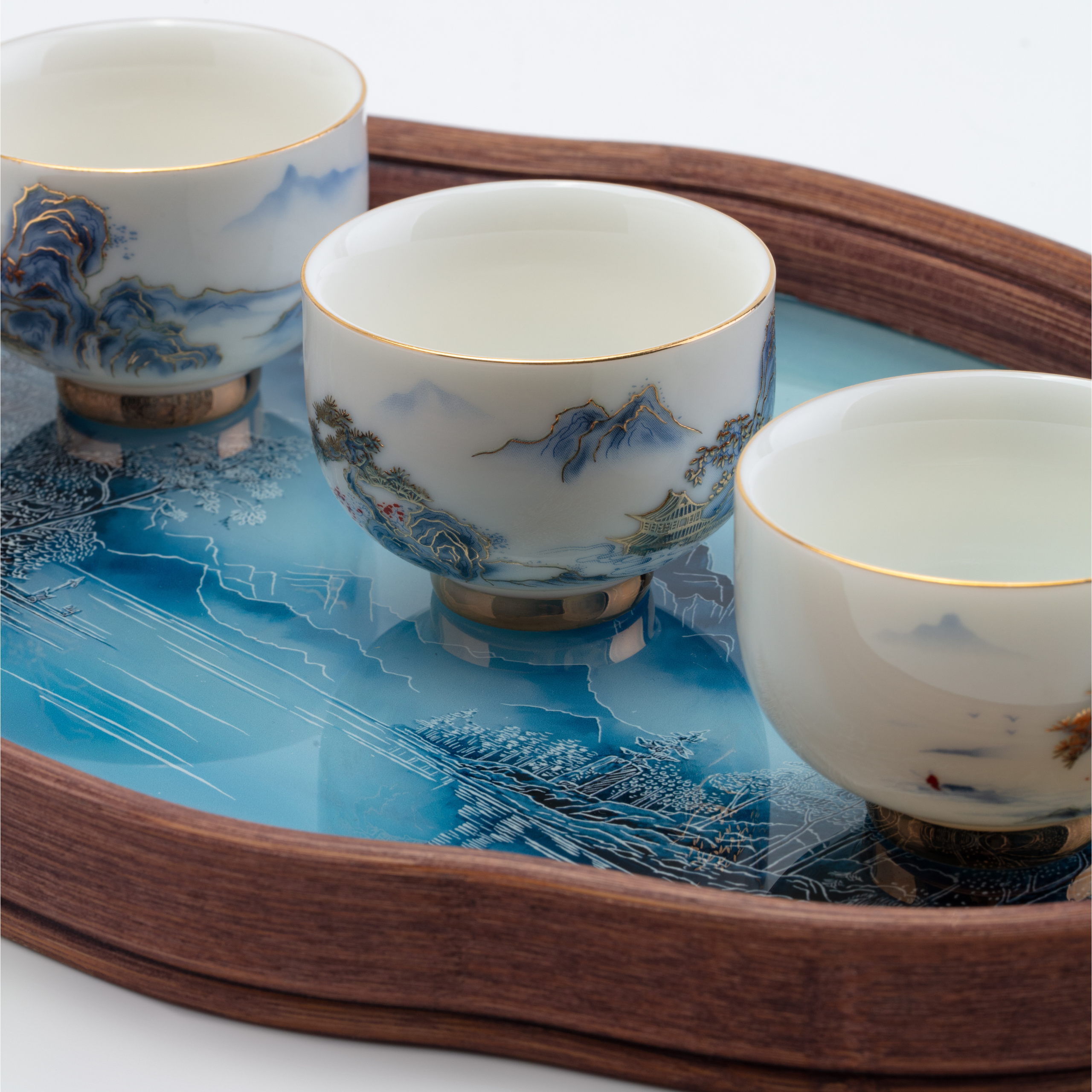 Three ceramic cups with artistic designs on a wooden tray