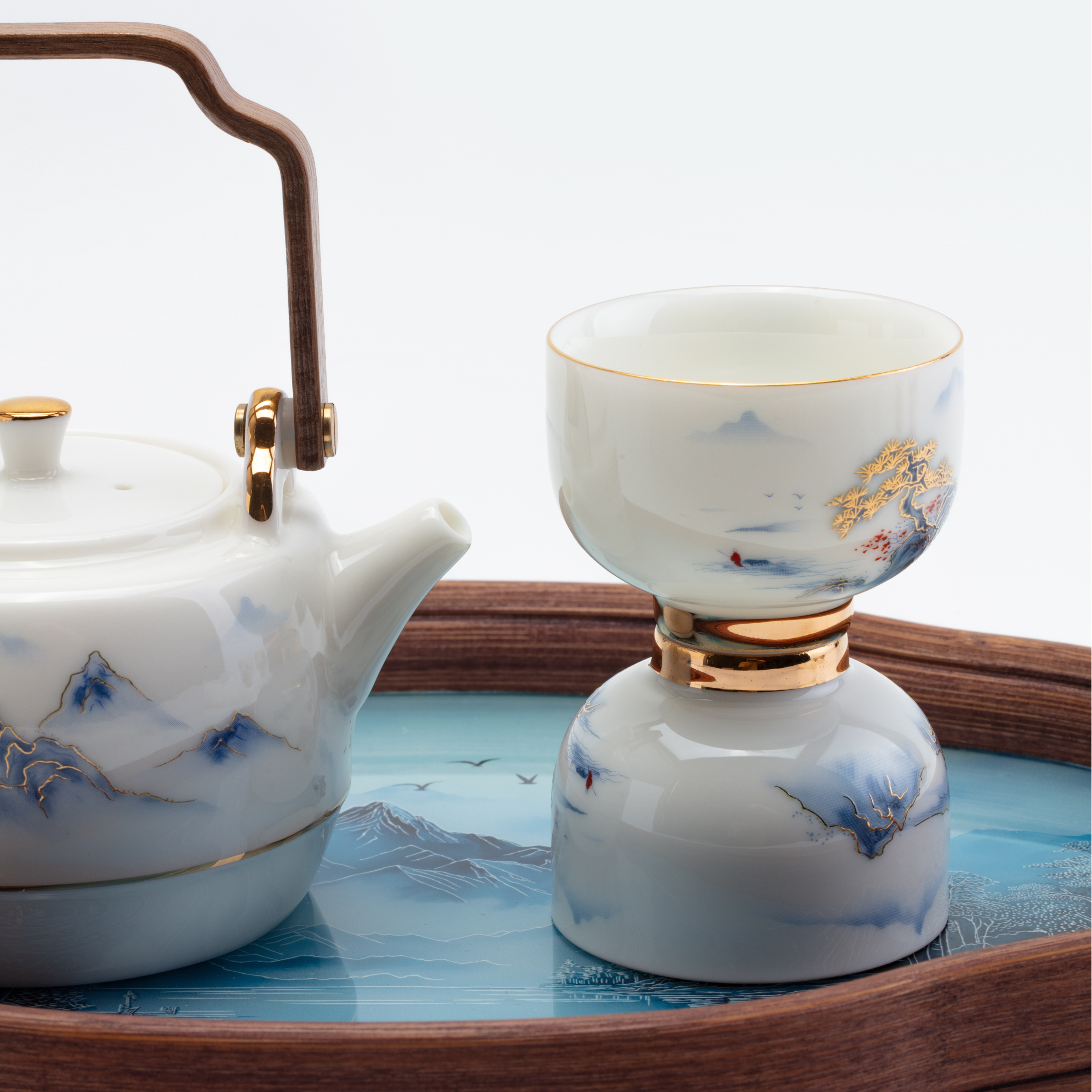Ceramic teapot and cup with artistic designs on a wooden tray