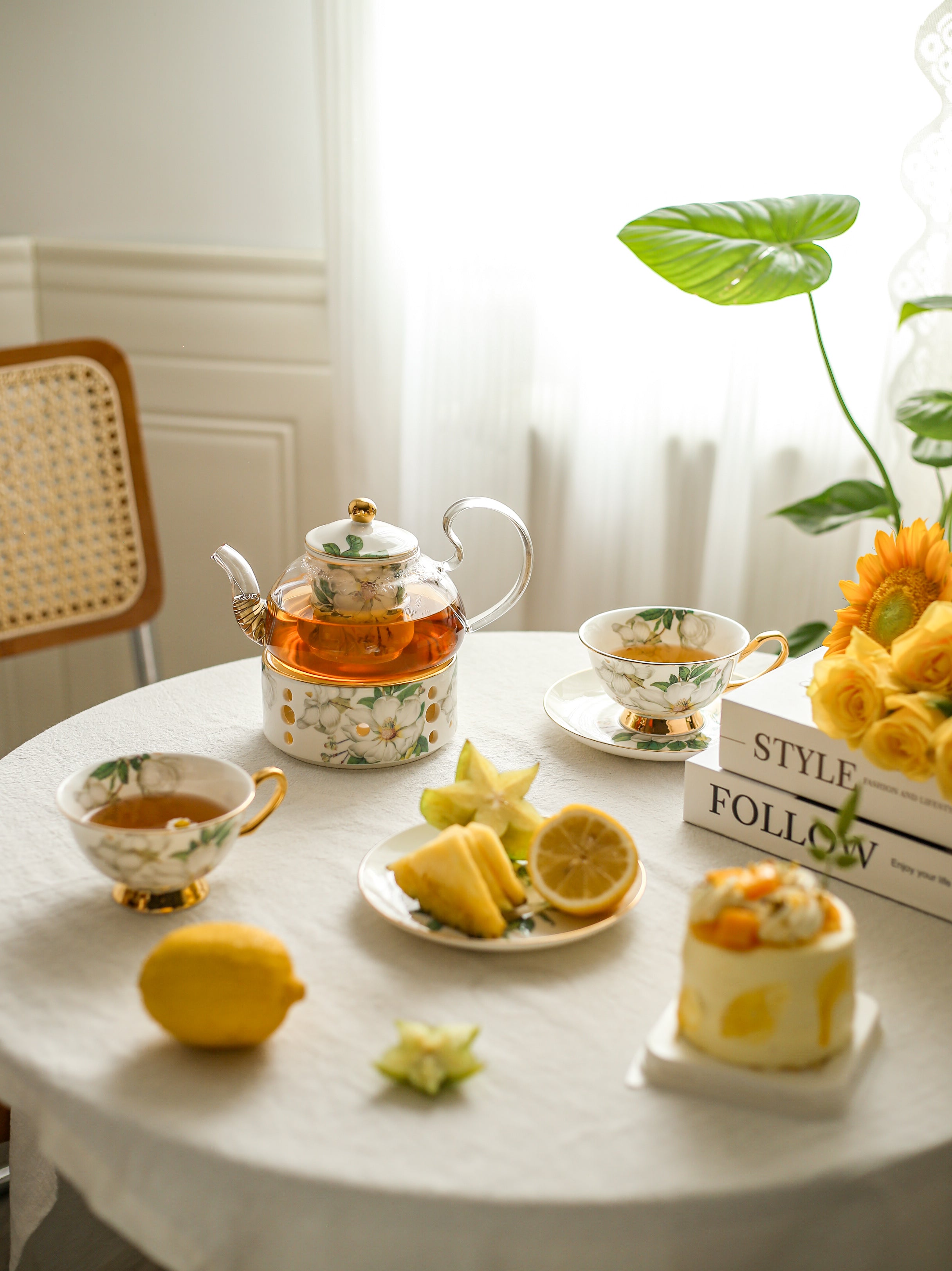 Tea set with lemon slices and a small cake on a table with a decorative background.