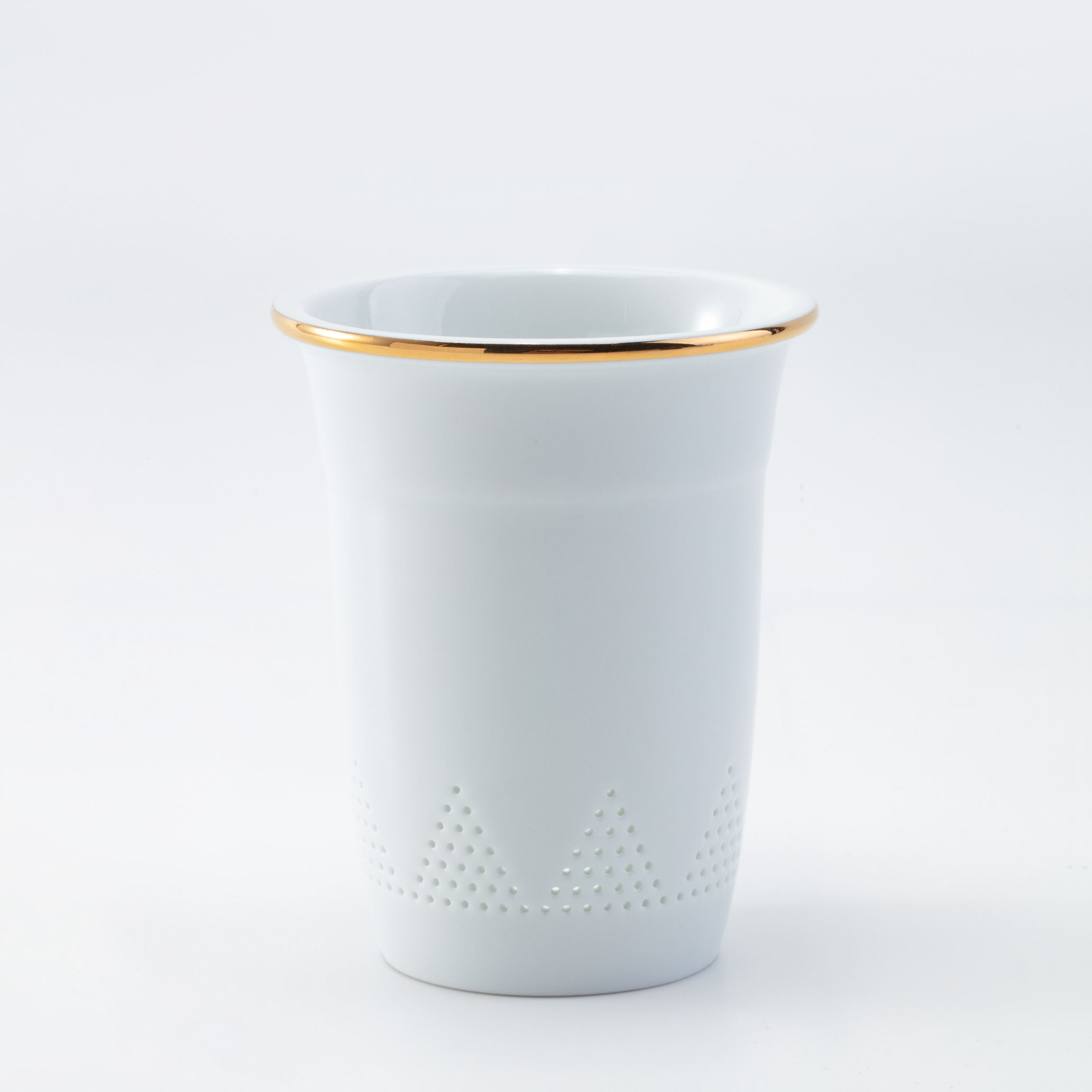 White ceramic cup with gold rim on a light gray background