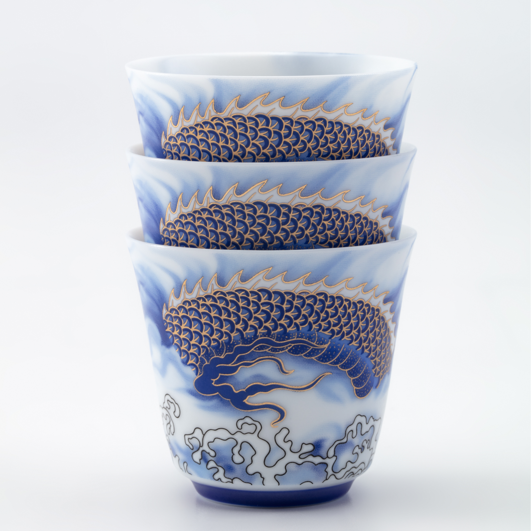 Set of three ceramic cups with dragon design on a white background