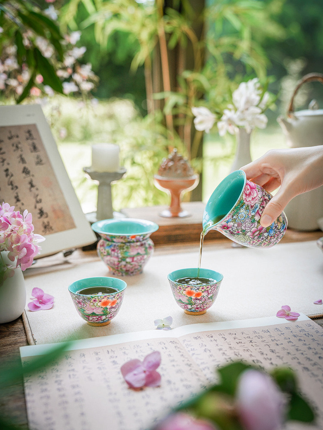 Tea ceremony with floral teacups and a teapot in a serene setting.