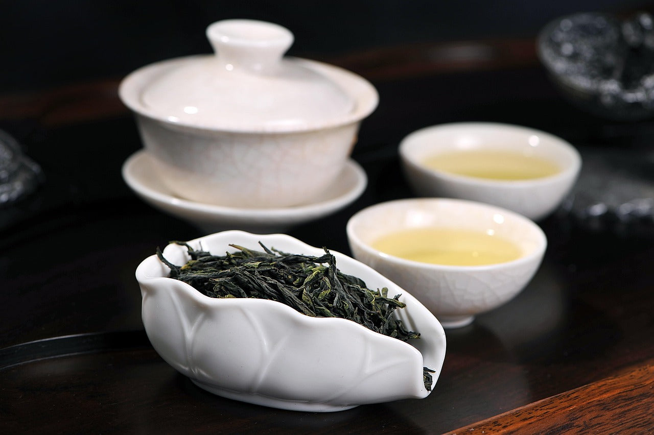 fresh tea leaves and white ceramic gaiwan kungfu tea set