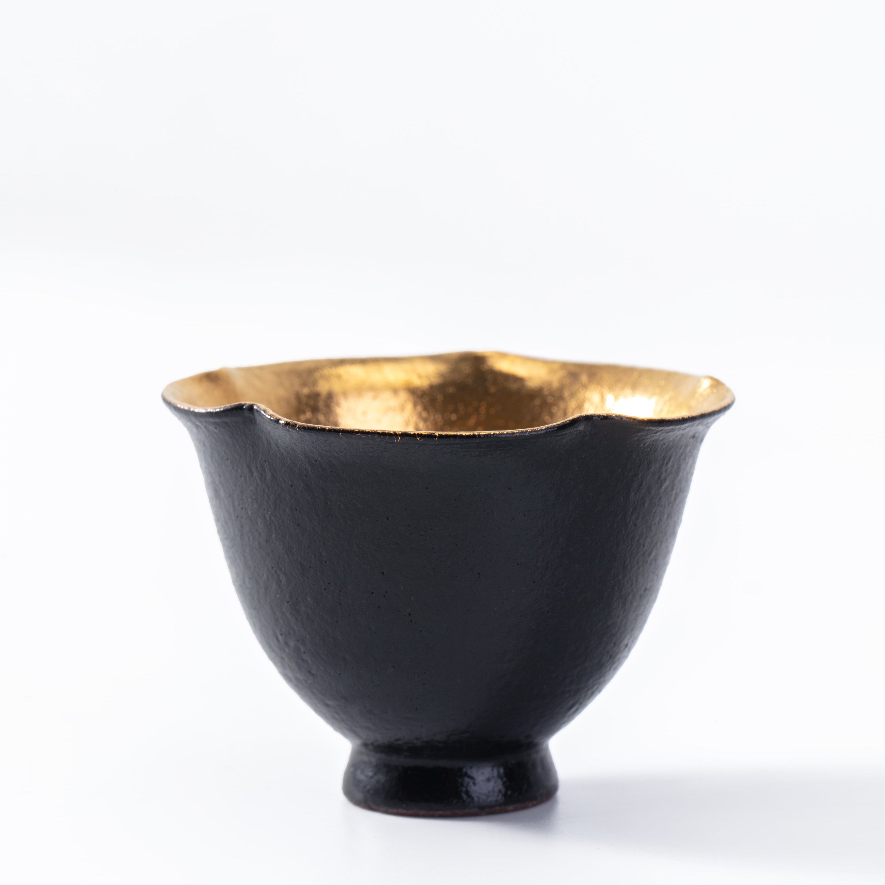 Black bowl with gold interior on a white background
