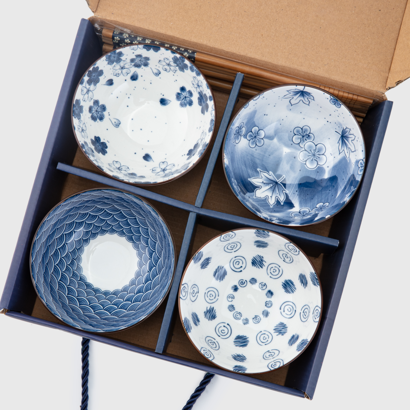 Set of four blue and white ceramic bowls in a box with a rope handle.