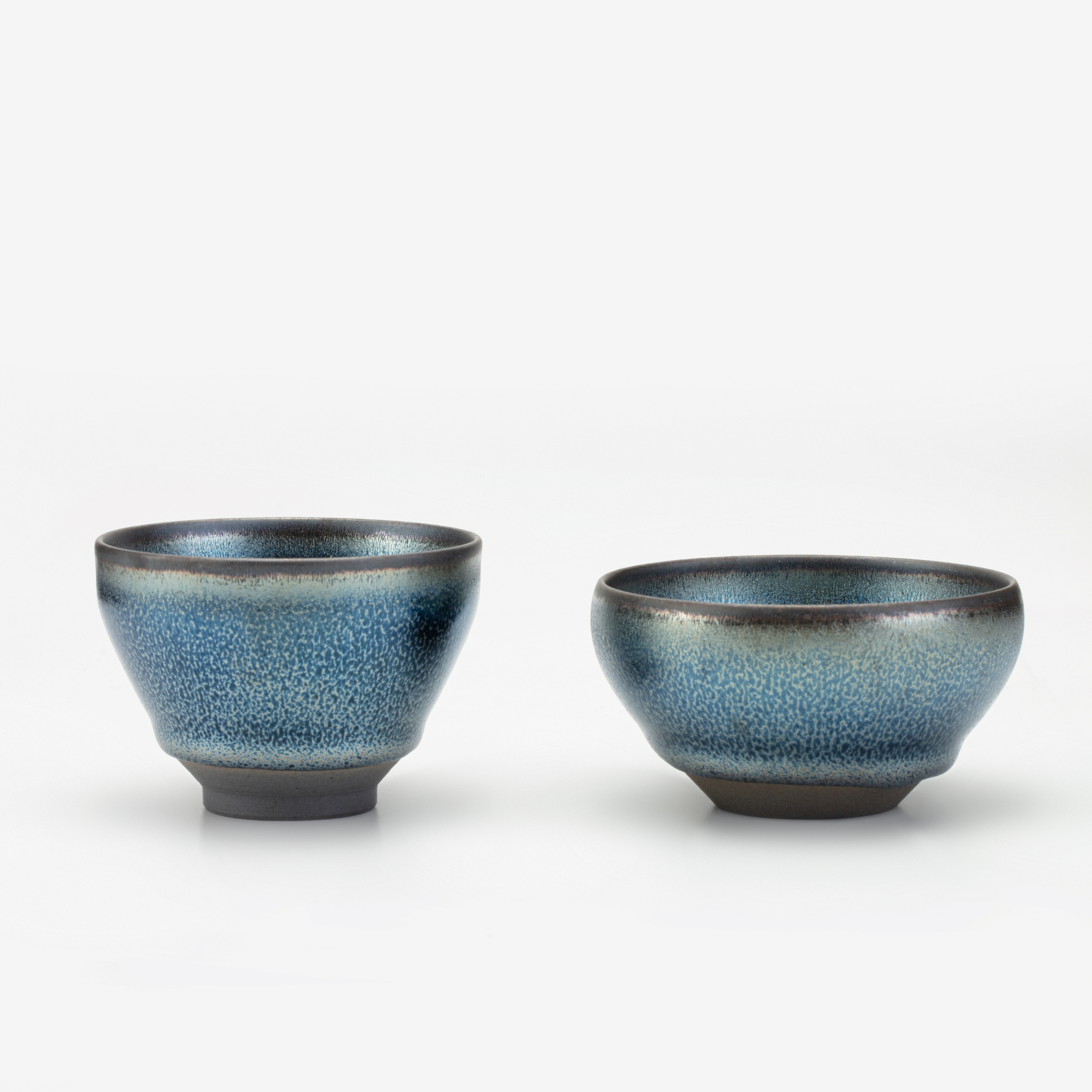 Two ceramic bowls with a blue glaze on a white background