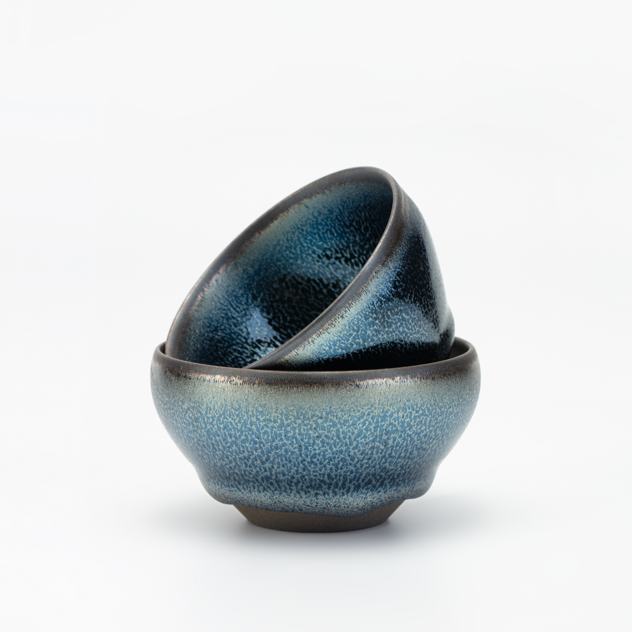 Two blue ceramic bowls stacked on a white background